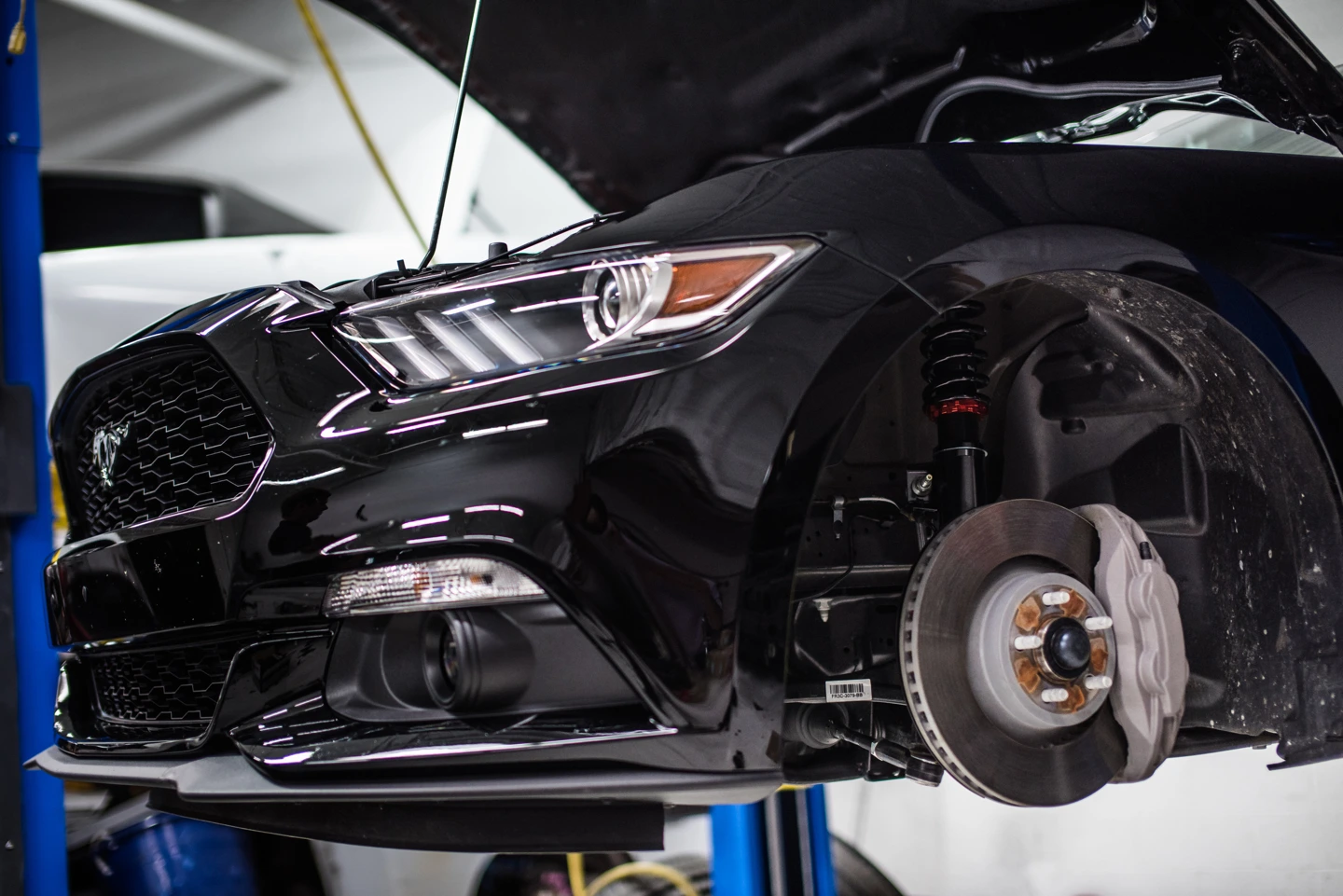 Original workshop photograph of a Ford Mustang during KSport suspension installation